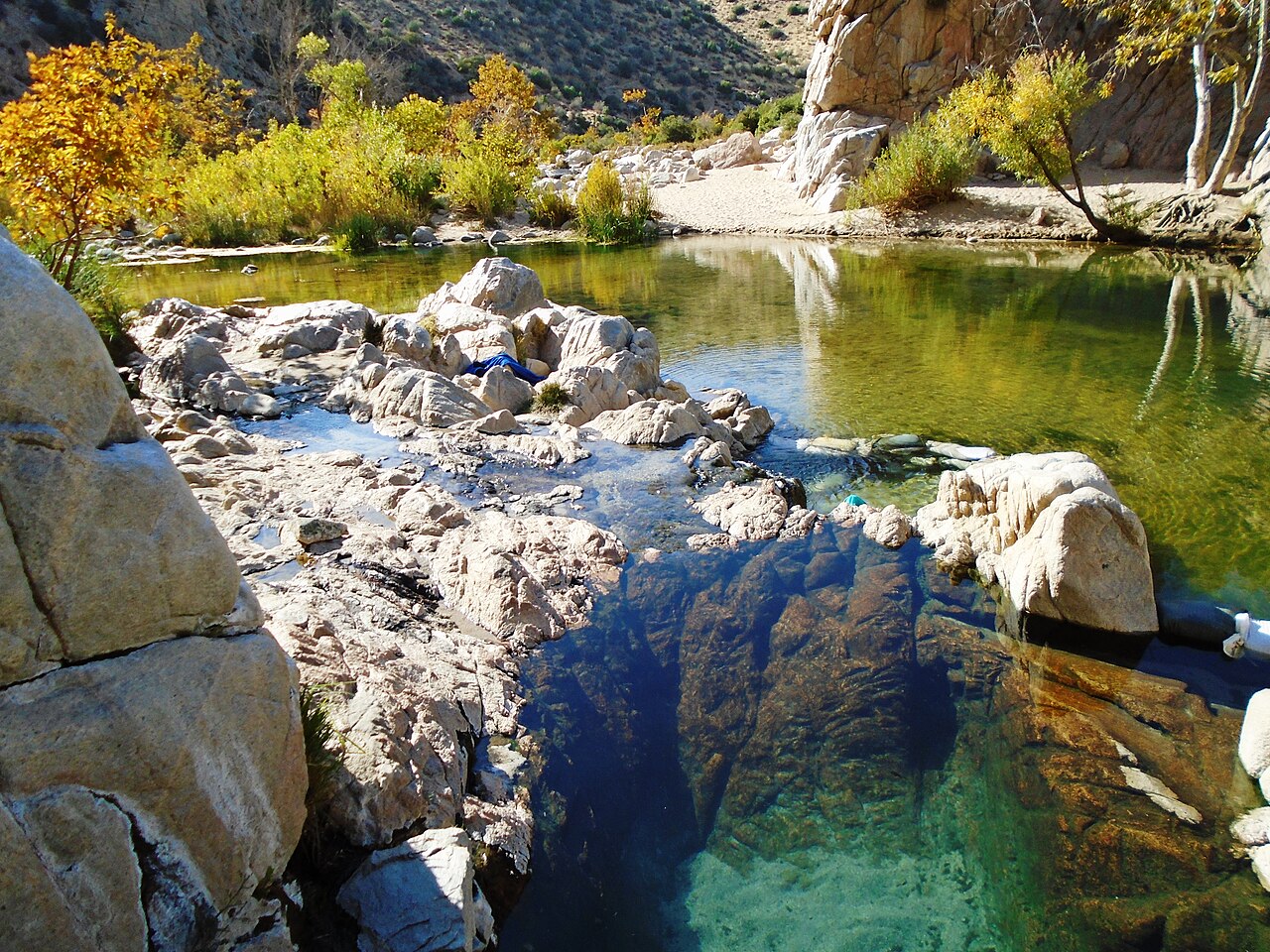 Clear warm pool beside Deep Creek with autumn trees and canyon walls